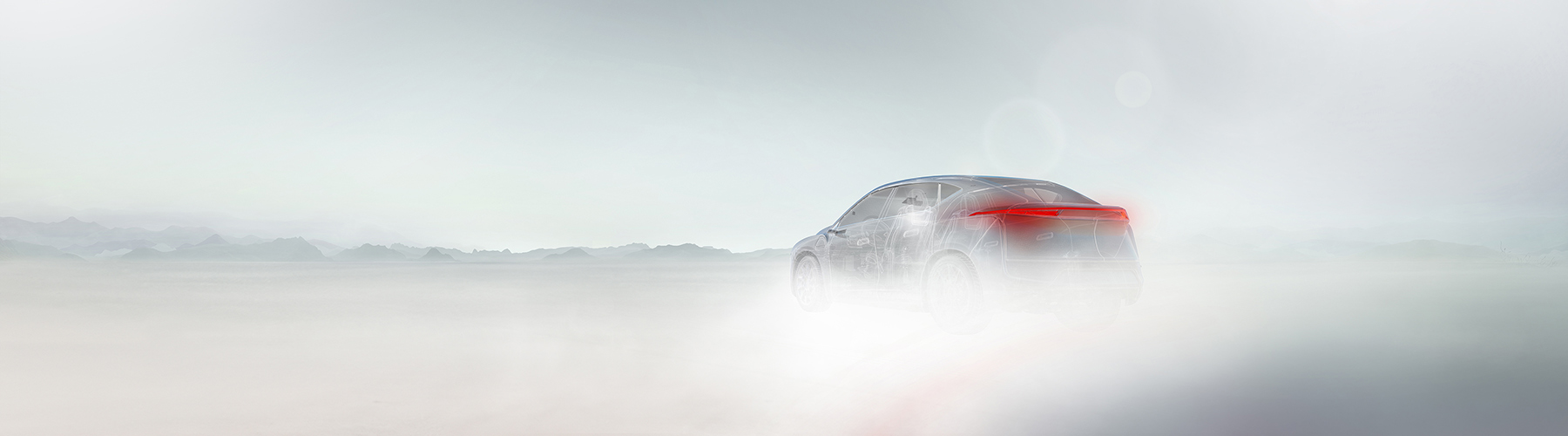 Ghosted vehicle driving along a road with fog and mountains in the foreground